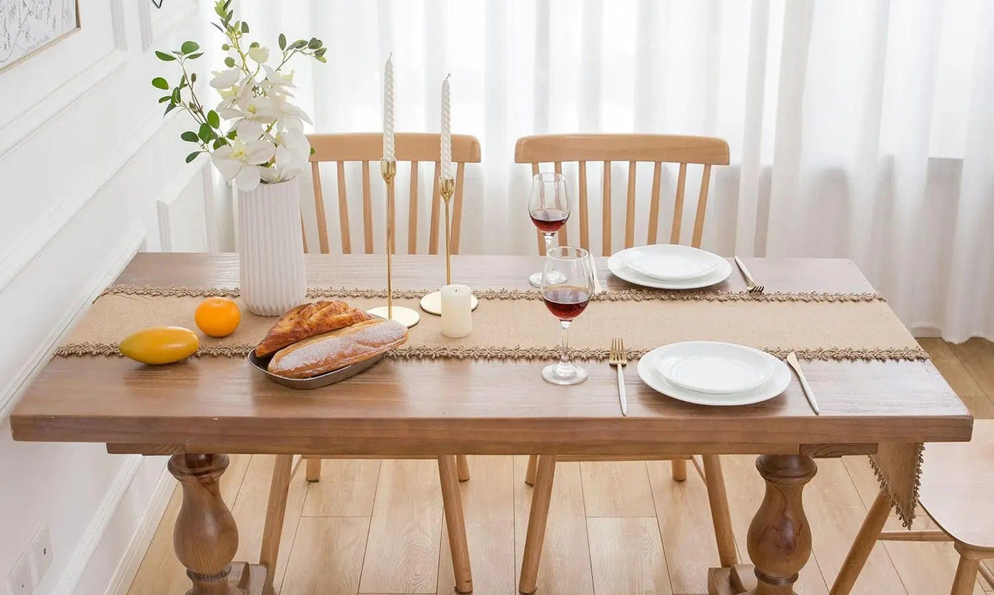 Dining table set with plates, glasses, and bread in a bright room.
