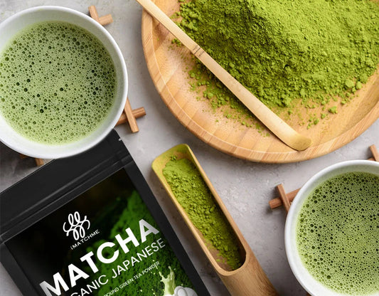 Matcha green tea powder with two cups of matcha, a scoop, and packaging on a gray surface.