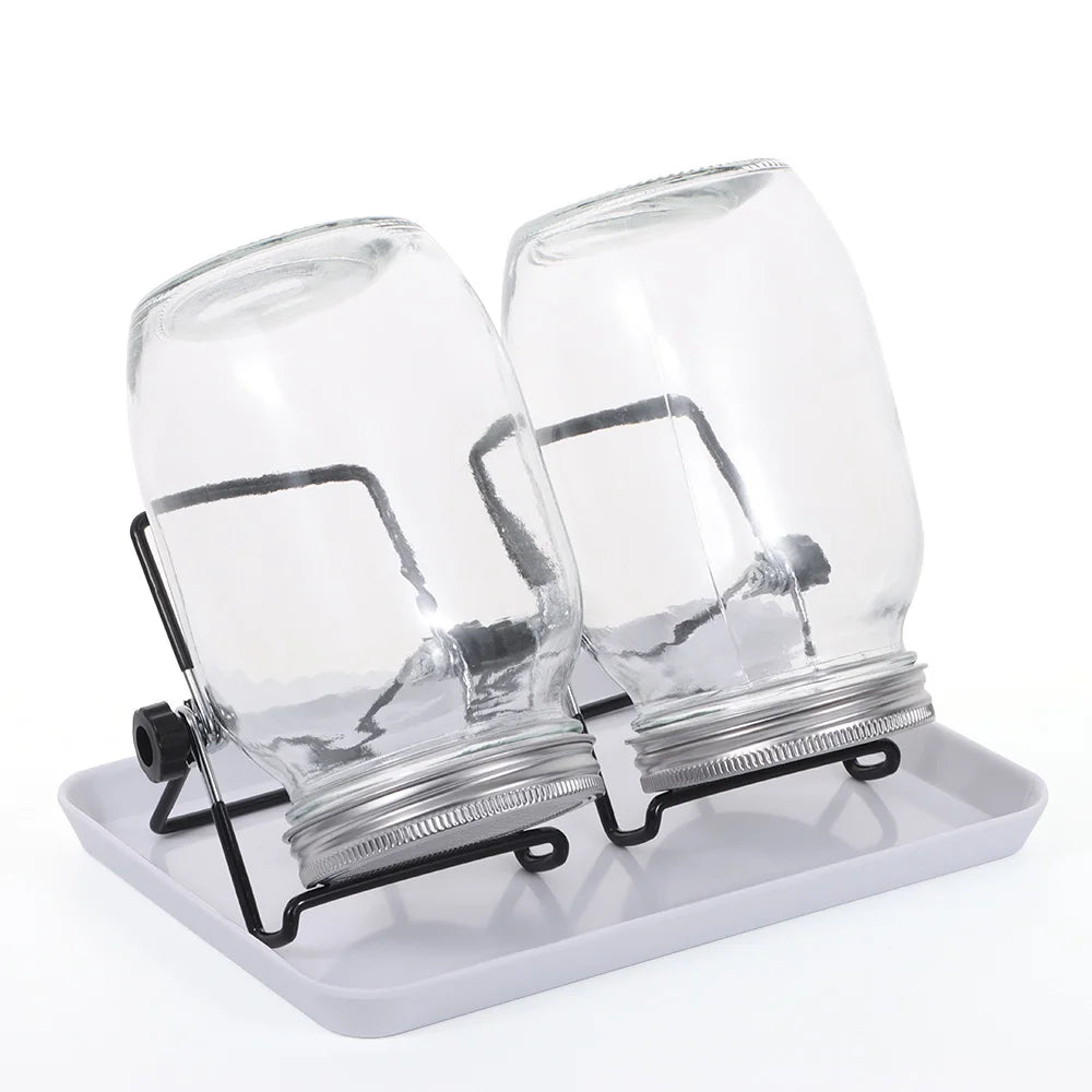 Two clear glass jars with metal lids on a white tray against a white background