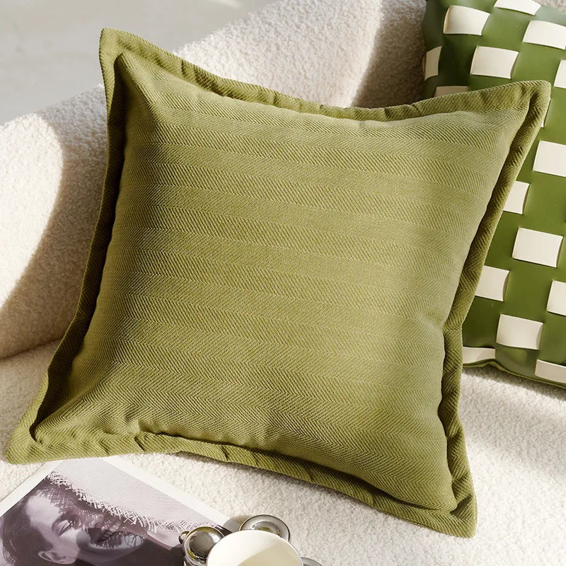 Green pillow on a couch with another green pillow featuring white squares in the background.