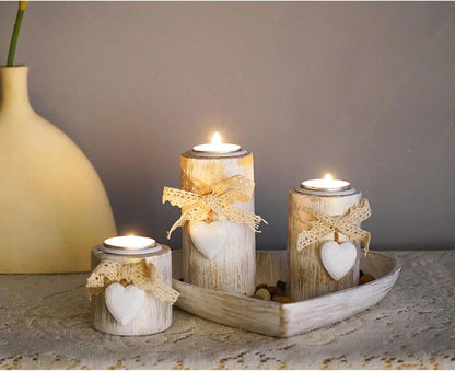 Decorative candles with heart shapes on a wooden tray, with a vase in the background.
