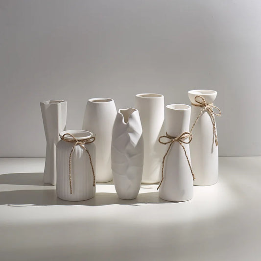 Set of white ceramic vases with string bows on a light background