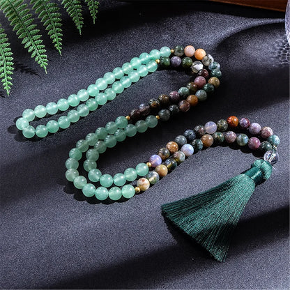 Multicolored beaded necklace with a green tassel on a dark fabric background