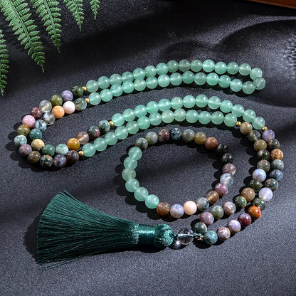 Multicolored beaded necklace with a green tassel on a dark fabric background