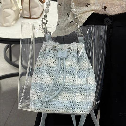 Crocheted bucket bag with a transparent strap over a clear stand