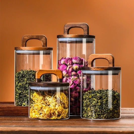 Set of glass jars with wooden lids containing different types of dried herbs on a wooden surface.