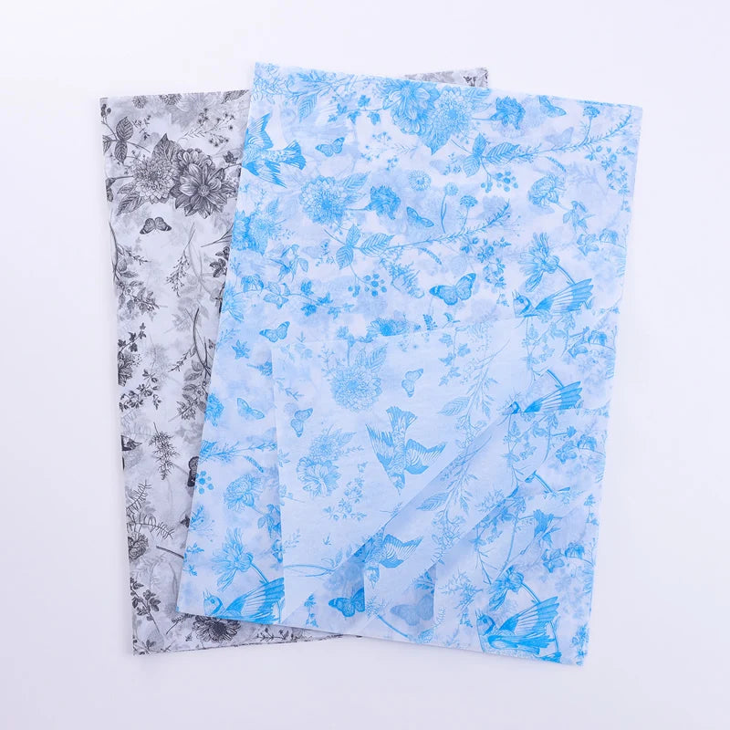 Two sheets of patterned paper, one with blue floral design and the other with gray floral design, on a white background.