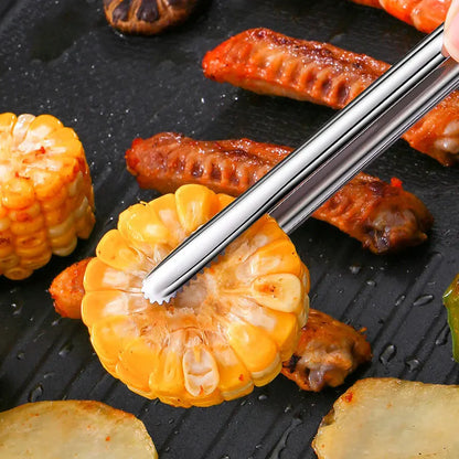 Cooking scene with corn, sausages, and a hand using tongs on a grill.