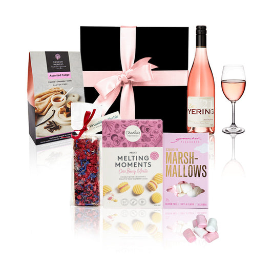 Gift set with pink wine, cookies, and candy on a white background