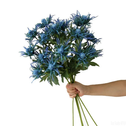 Bouquet of blue flowers held by a hand on a white background