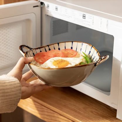 Person holding a bowl of food in front of an open microwave.