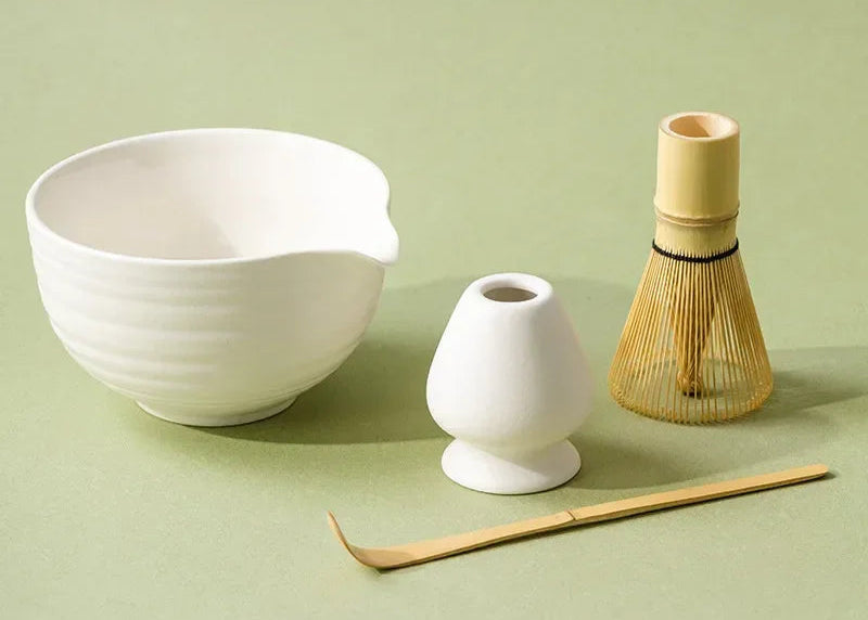 Ceramic tea bowl, whisk holder, and whisk on a green background
