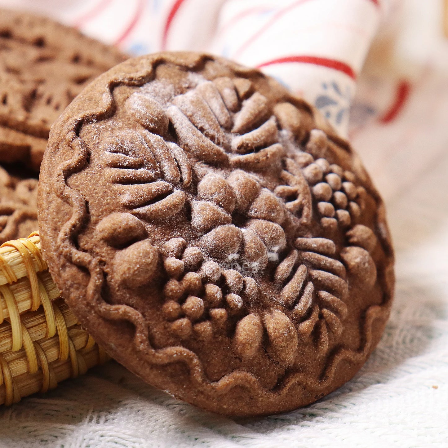 Decorative chocolate cookie with floral patterns on a textured surface