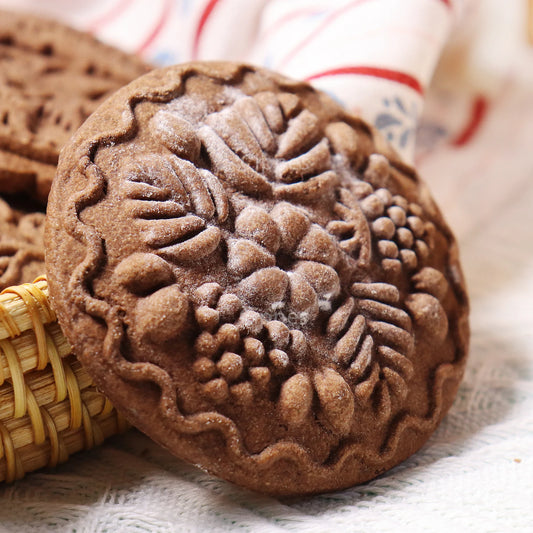 Decorative chocolate cookie with floral patterns on a textured surface