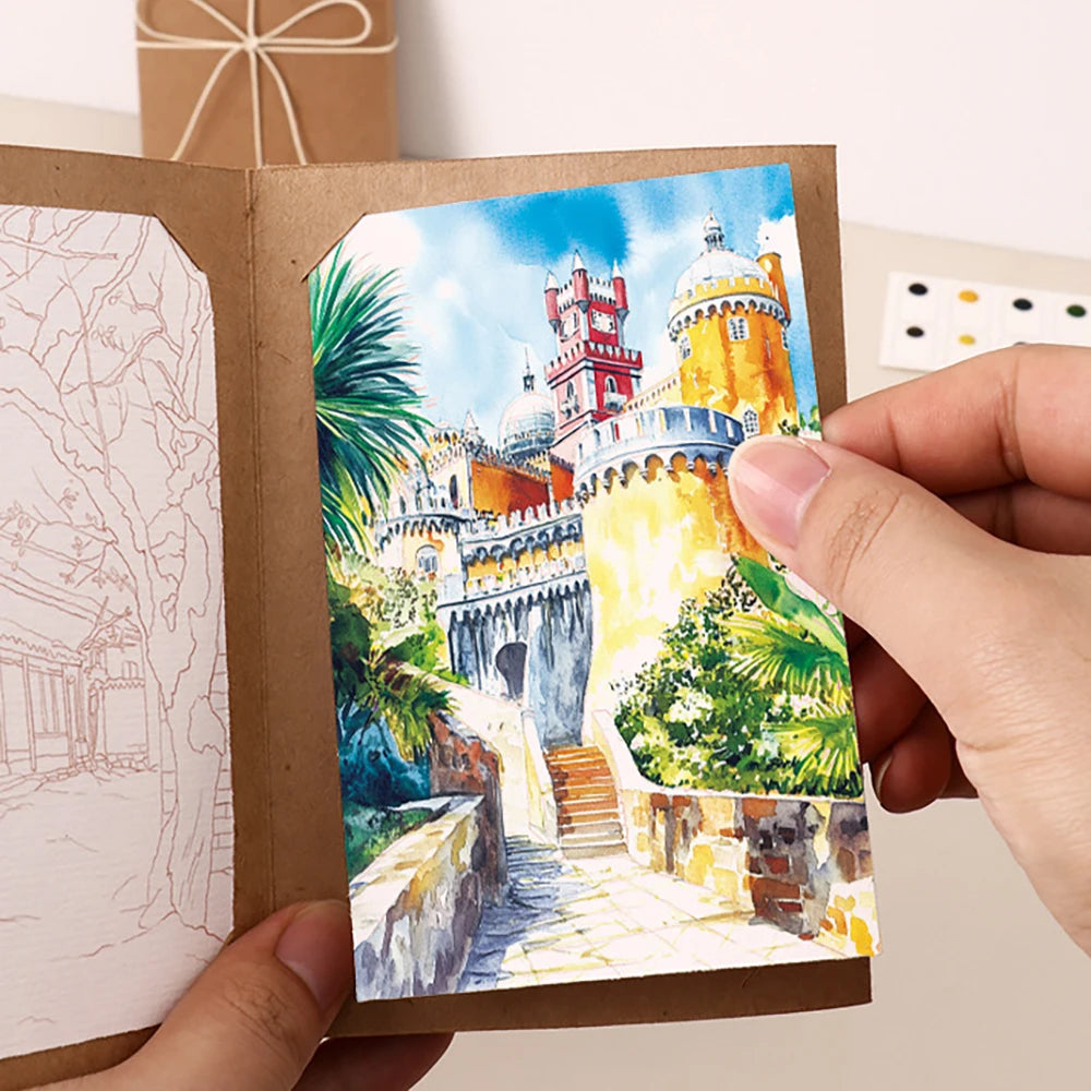 Hand holding a small painting of a castle with greenery