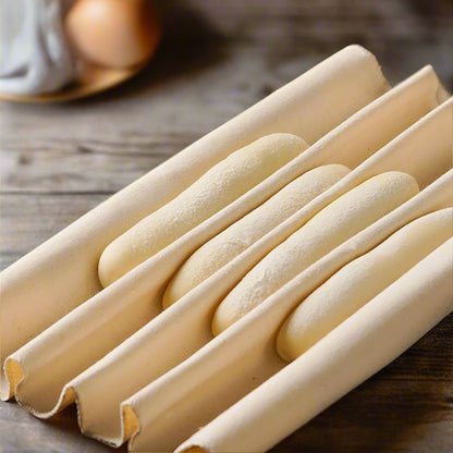 Breadsticks on a wooden surface with strawberries in the background