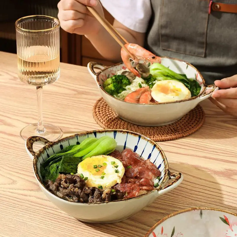 Two bowls of food on a wooden table with a glass of white wine.