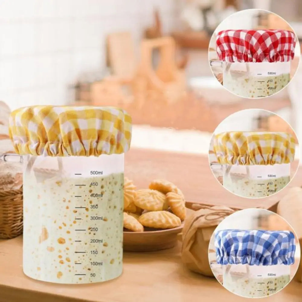 Measuring cup with checkered coverings on a kitchen counter with cookies and a basket.