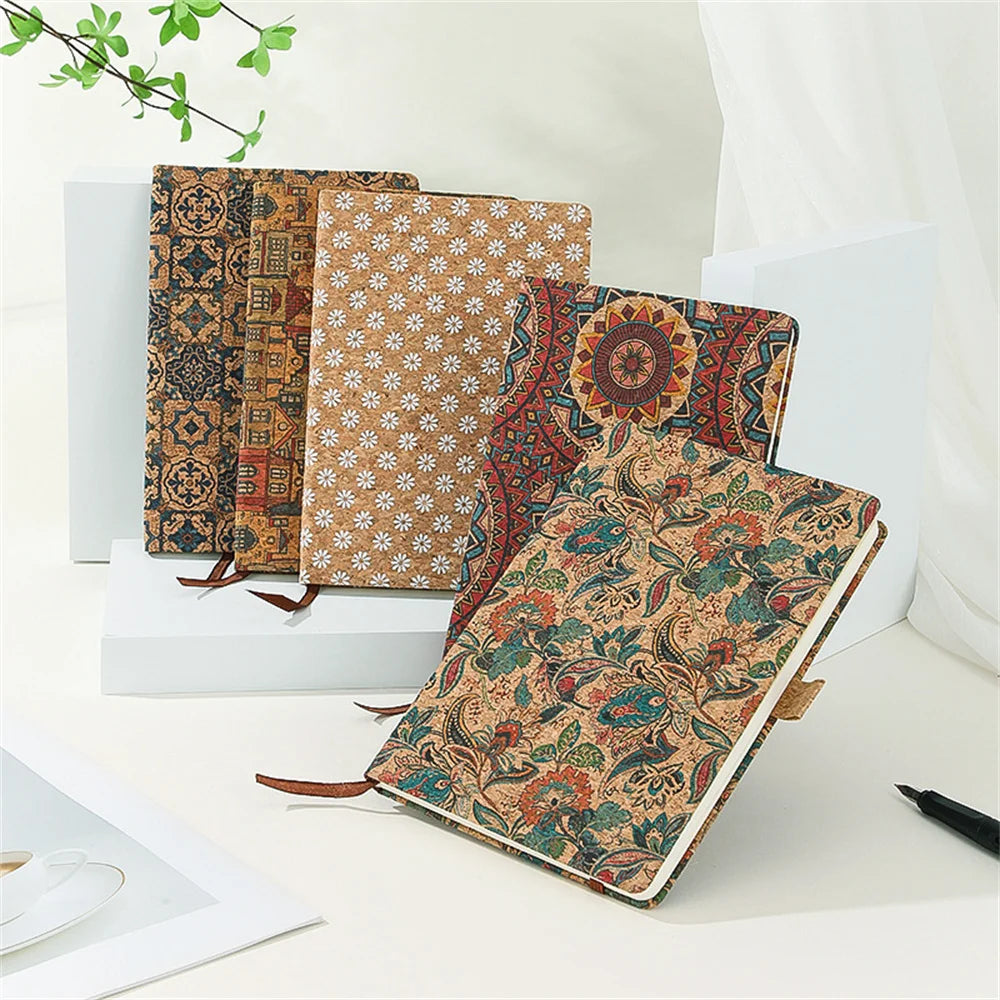 Three patterned notebooks on a white surface with a plant in the background
