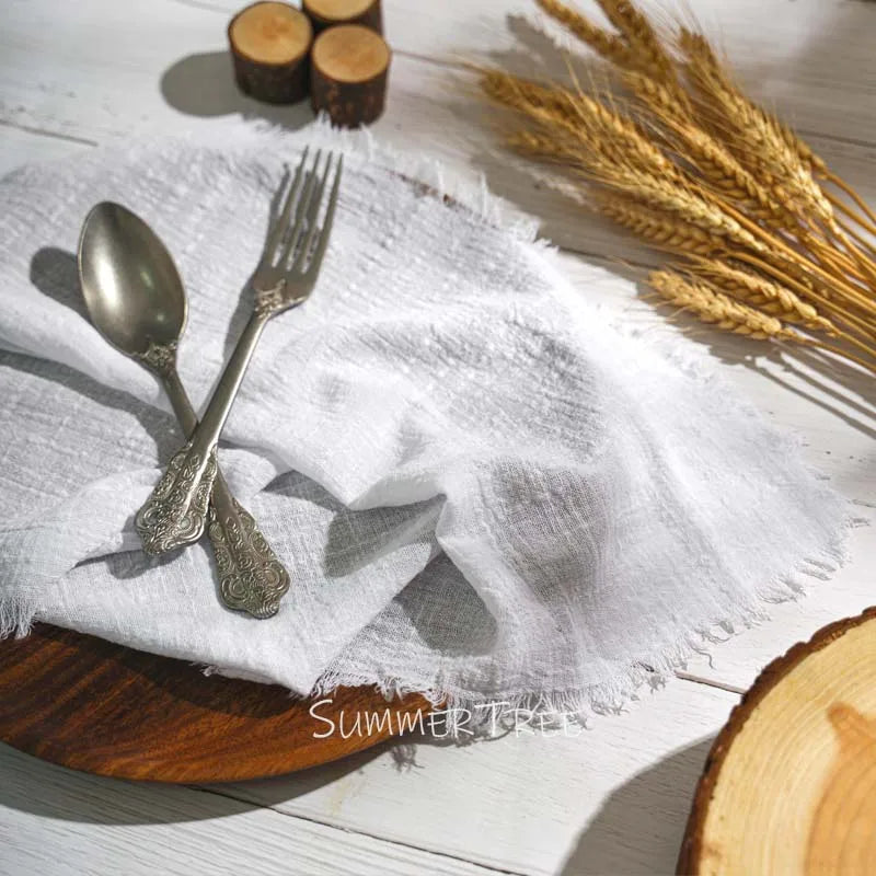 Silver spoon and fork on a white cloth with wooden elements and wheat stalks.