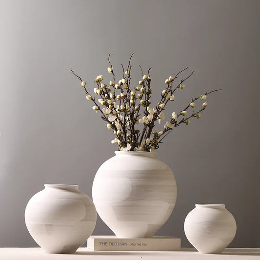Set of three white ceramic vases with a book and decorative branches on a gray background