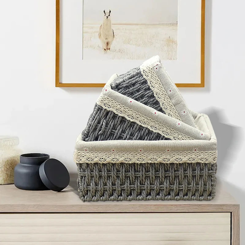 Woven storage basket with folded textured blanket on a wooden surface, framed picture of llama in the background.