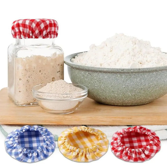 Bowl of flour, jar of salt, and small bowl on a wooden board with decorative lids.
