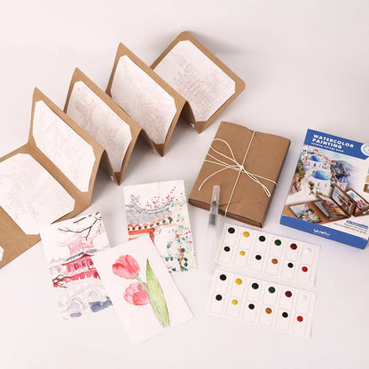 Artistic supplies including watercolor books, cards, and color swatches on a white surface.