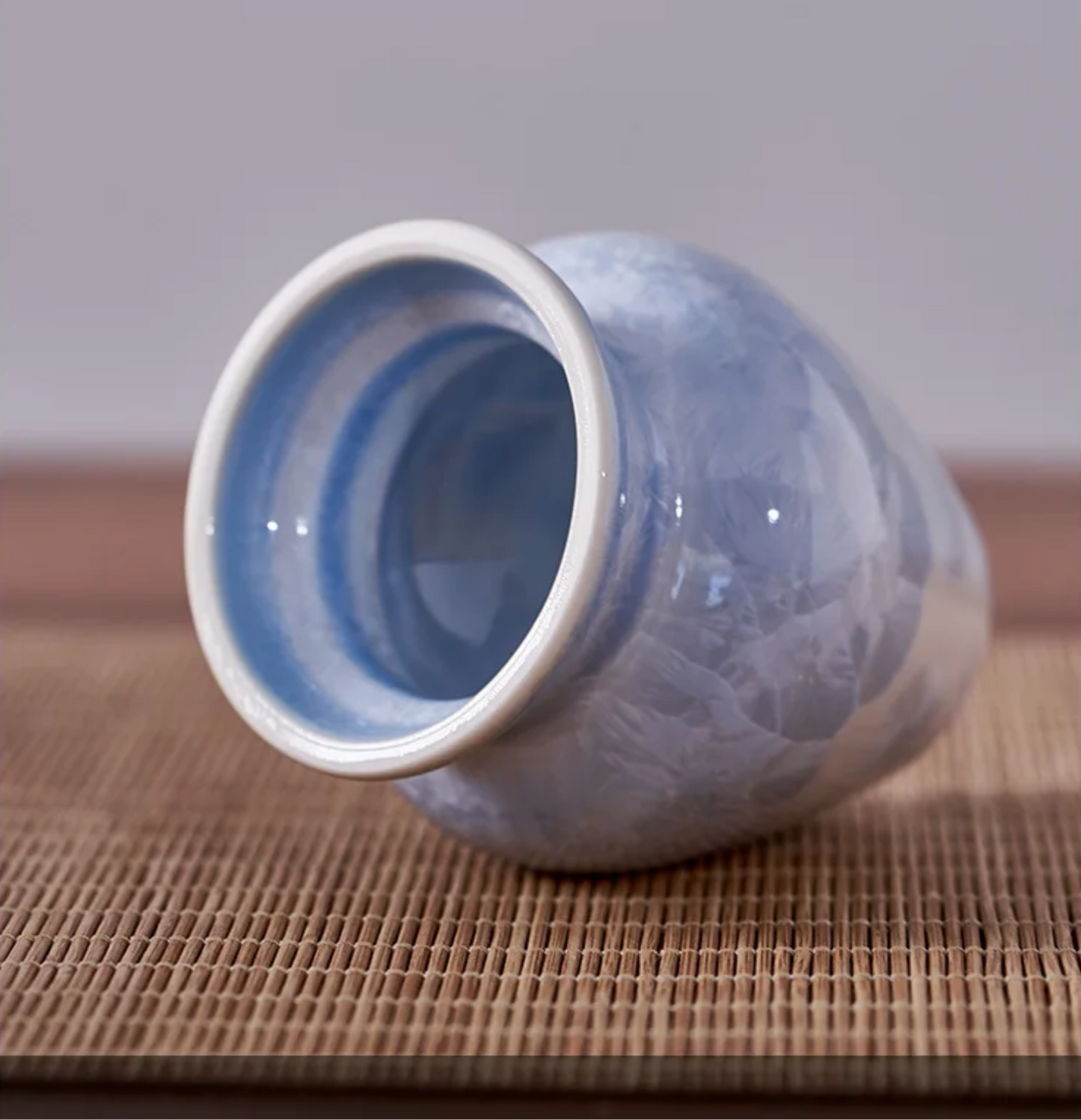 Blue ceramic vase on a textured surface with a neutral background