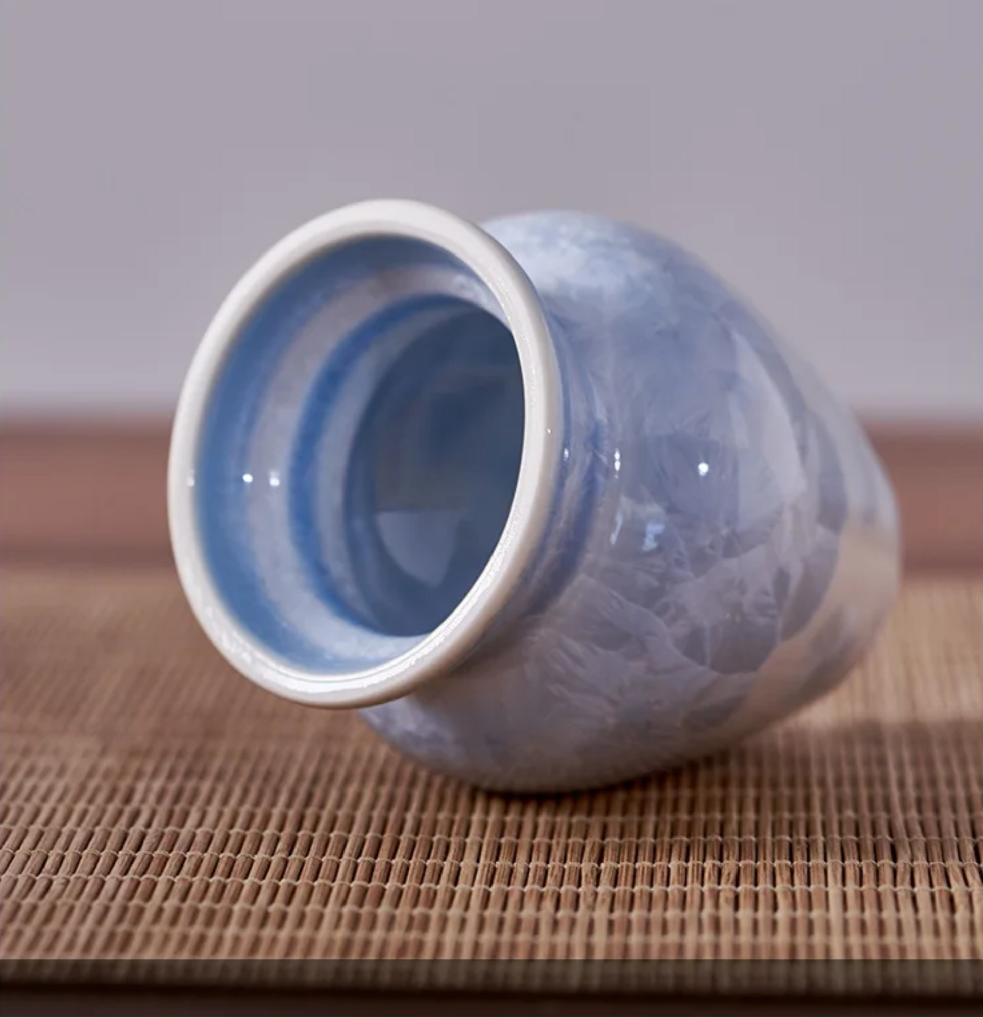 Blue ceramic vase on a textured surface with a neutral background