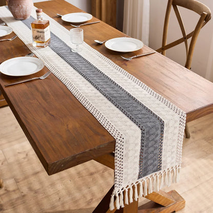 Wooden dining table with a striped table runner, plates, and cutlery.
