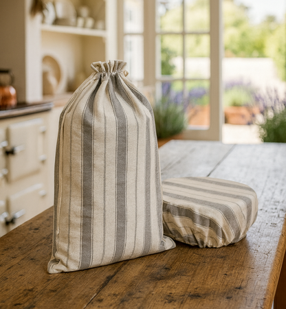 Striped fabric bag and cushion on a wooden table with a kitchen and garden view in the background