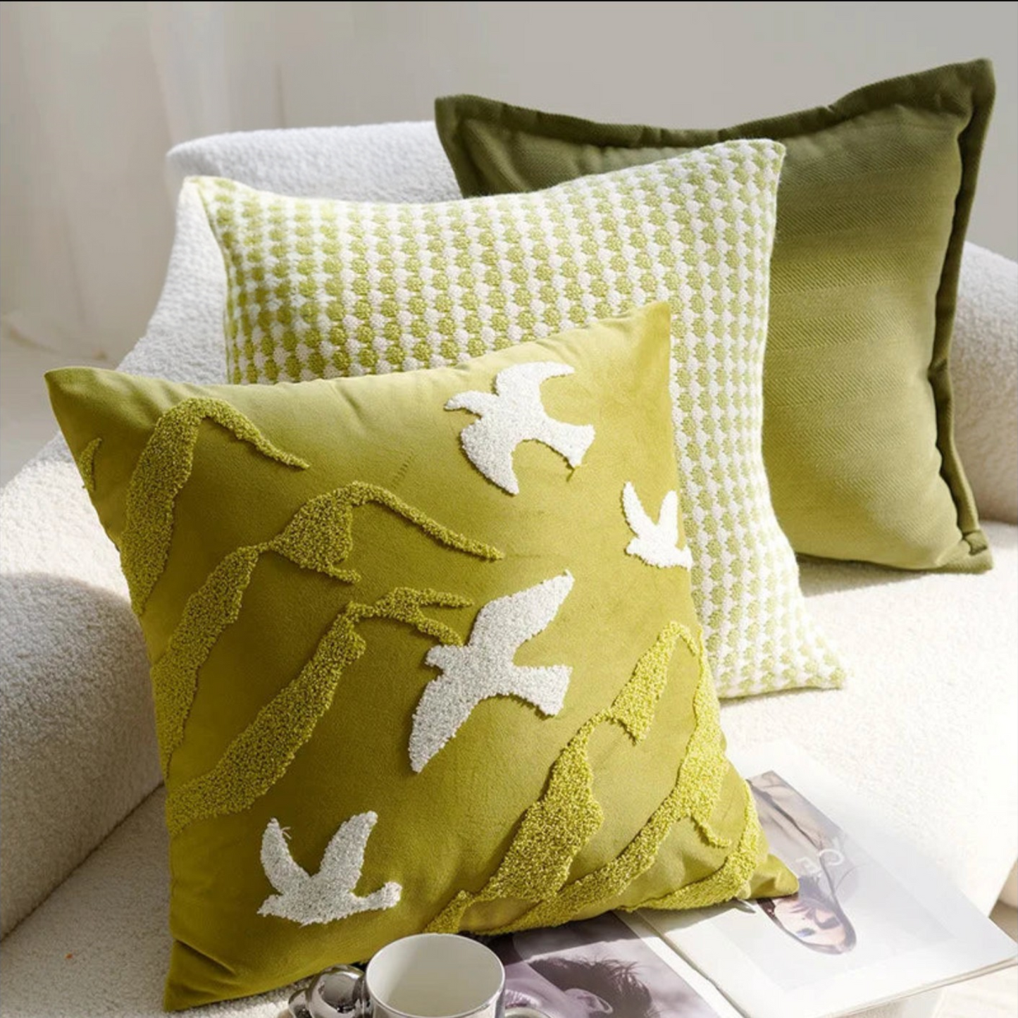 Three decorative pillows on a couch with a focus on a green pillow with bird patterns.
