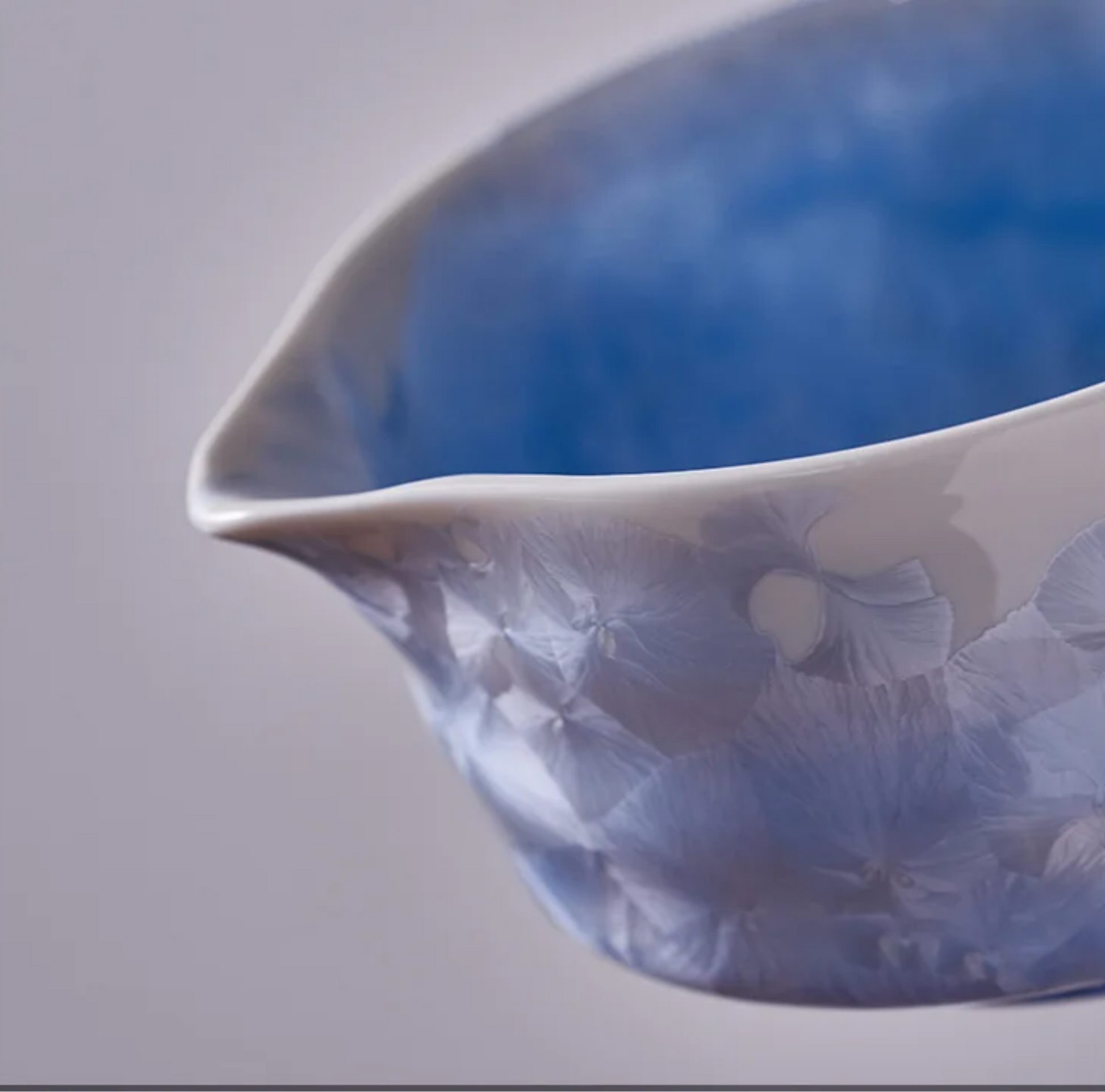 Blue ceramic pitcher on a light gray background