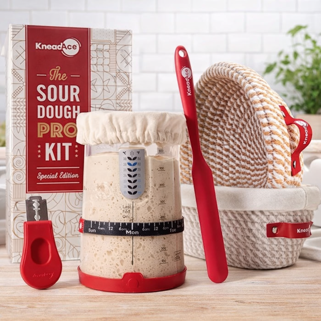 KneadAce sour dough kit with measuring container, red spatula, and basket on a wooden surface.