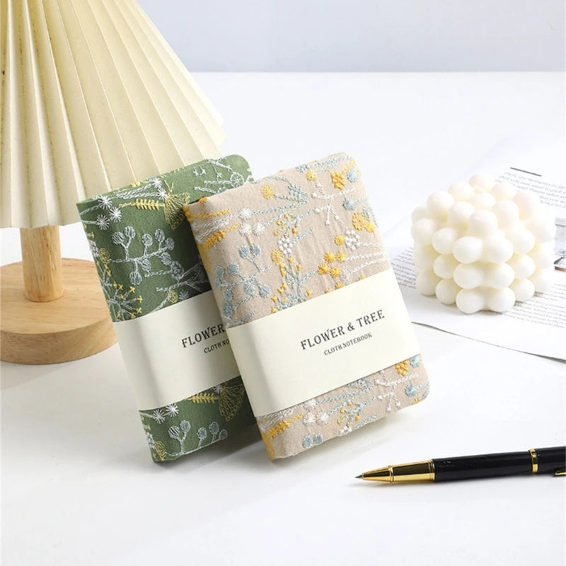 Two notebooks with floral designs on a white surface with decorative items.