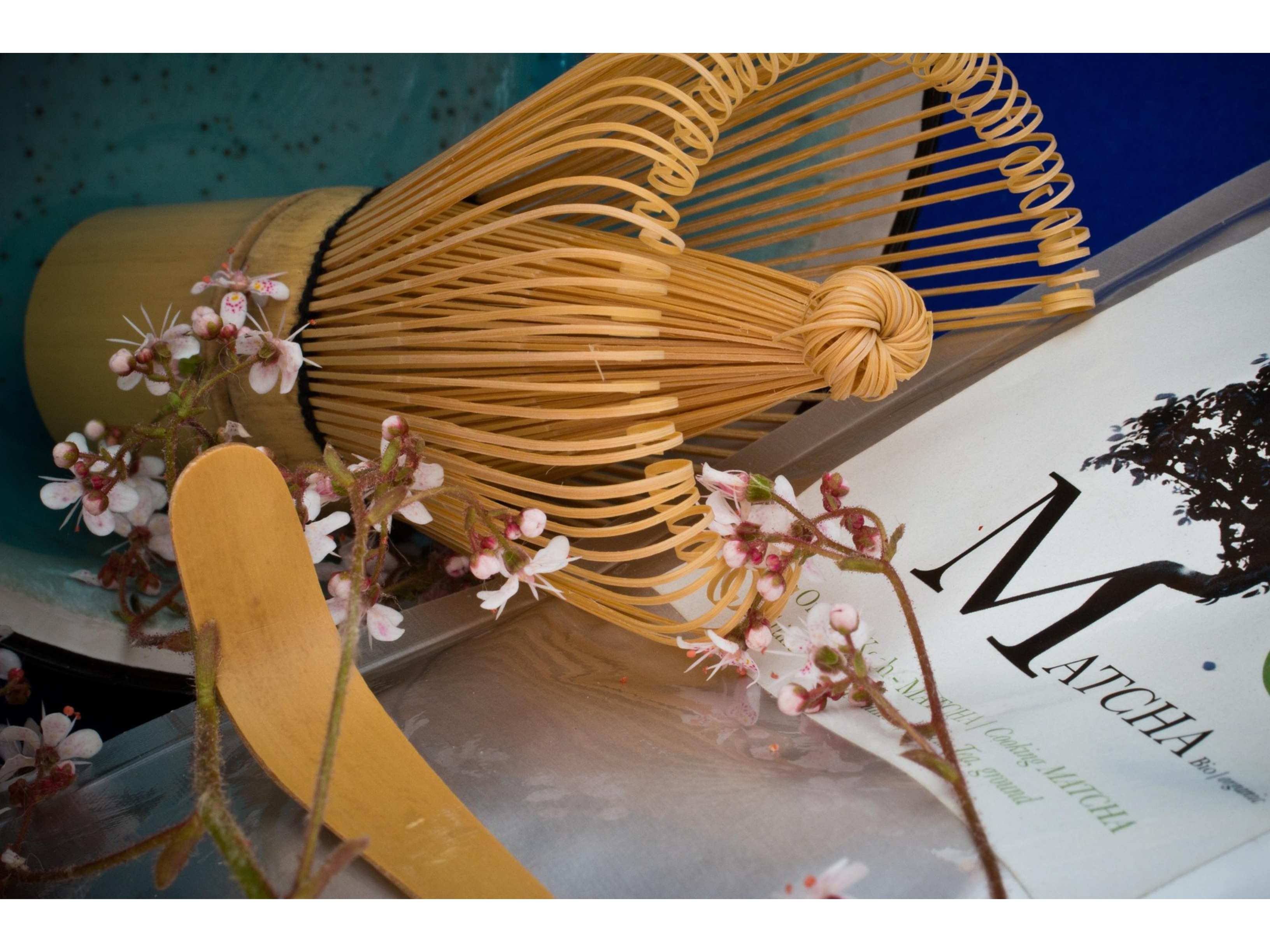 Yellow woven broom with floral decorations on a book titled 'Matcha'.