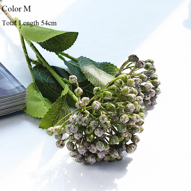 Artificial flower branch with green leaves and small flowers on a white background