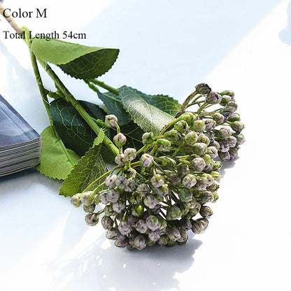 Artificial flower branch with green leaves and small flowers on a white background