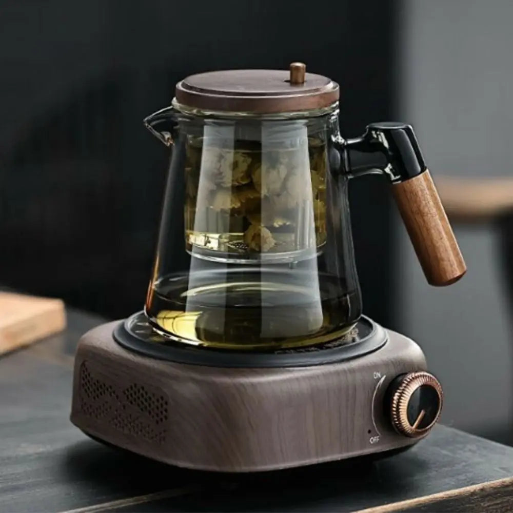 Glass teapot with wooden handle and base on a black surface