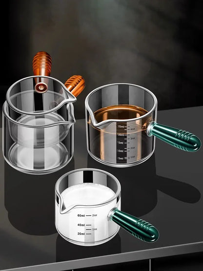 Set of glass measuring cups with handles on a dark surface