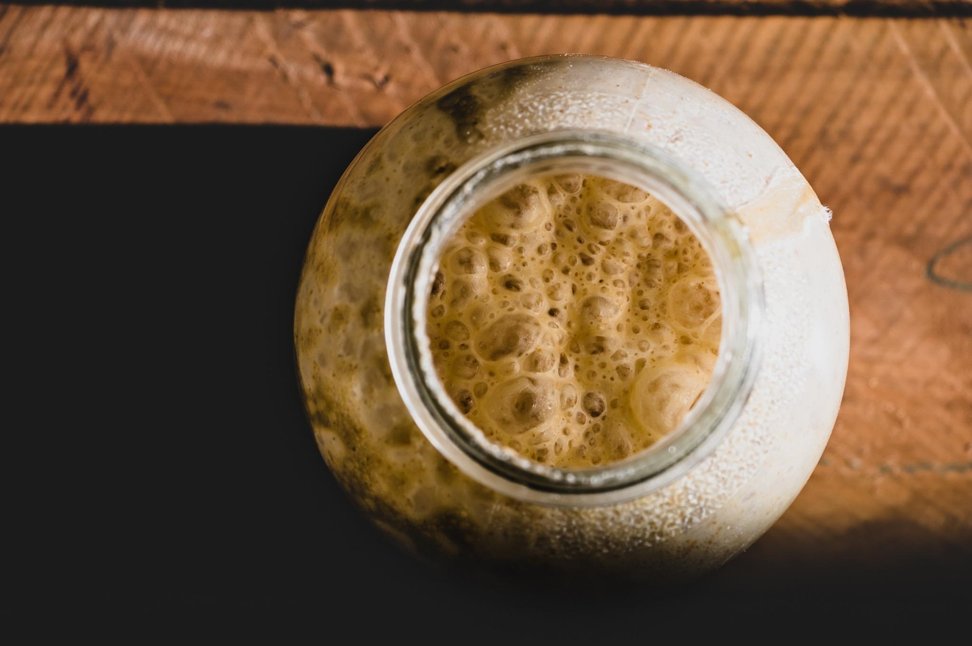 Close-up of a glass jar with a brown liquid on a wooden surface
