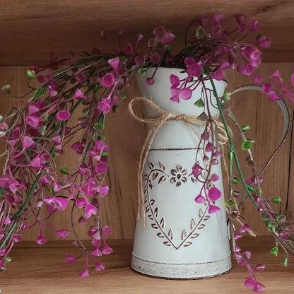 Decorative white pitcher with pink flowers on a wooden surface