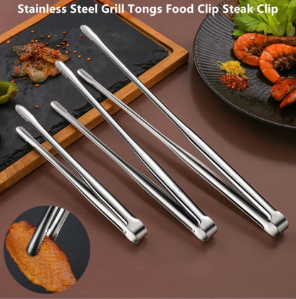 Set of stainless steel grill tongs on a brown surface with food in the background