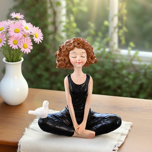 Decorative figurine of a woman in a yoga pose with a white dove and flowers on a table.
