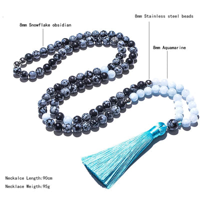 Necklace with snowflake obsidian, stainless steel beads, and aquamarine stones on a white background.