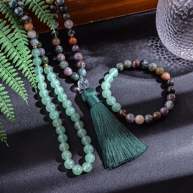 Beaded necklace and bracelet with tassel on a dark surface with fern leaves.