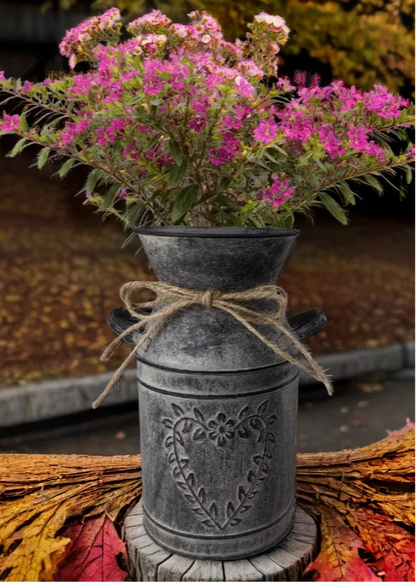 Decorative metal vase with pink flowers on a wooden stump with autumn leaves.