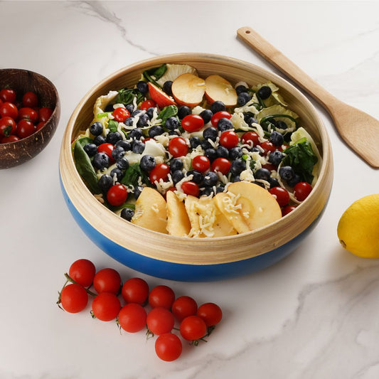 Salad with fruits and vegetables in a blue and wooden bowl on a marble surface