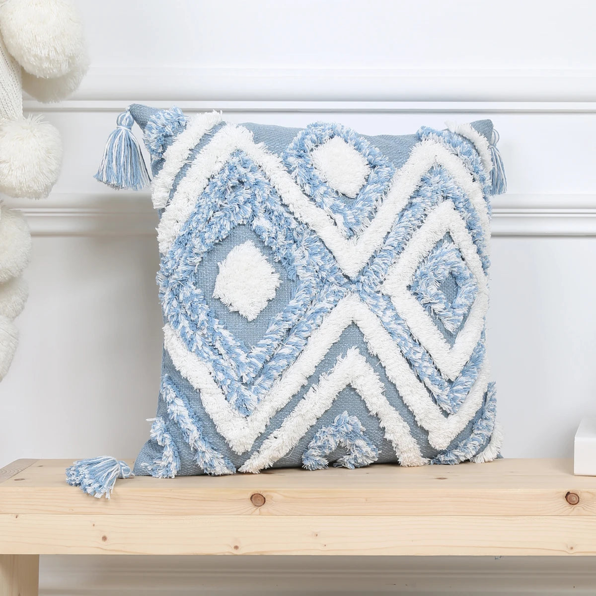 Decorative pillow with blue and white geometric pattern on a wooden bench.